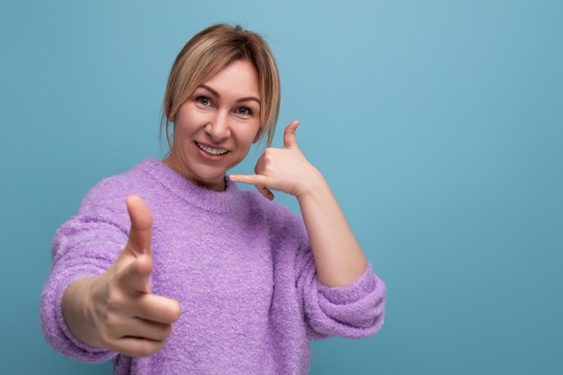 Sorridente giovane donna bionda elegante in un look casual con un buon umore tende la mano su un luminoso