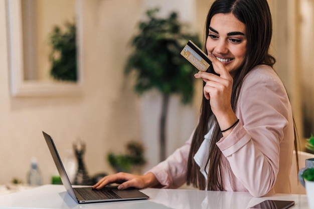 Sorridente giovane donna di affari che immette informazioni dalla carta sul computer portatile