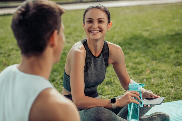 Sorridente giovane donna e uomo che parla nel parco dopo l'esercizio