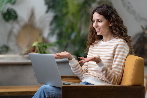 Sorridente giovane donna freelance progetto di pianificazione di lavoro tiene videoconferenza nello spazio di coworking