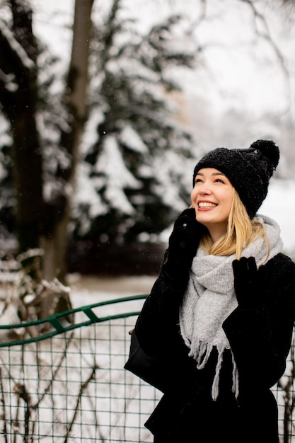 Sorridente giovane donna in abbigliamento accogliente utilizzando il telefono cellulare in giornata invernale