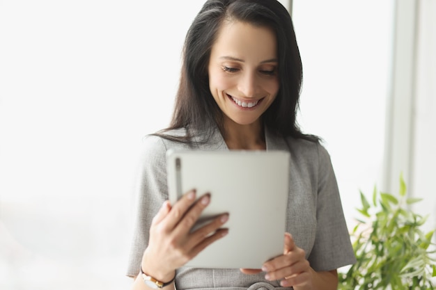 Sorridente giovane donna in tuta con tablet digitale