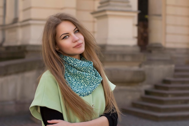 Sorridente giovane donna in un cappotto verde in strada