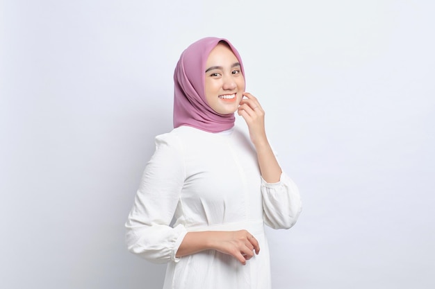 Sorridente giovane donna musulmana asiatica che guarda l'obbiettivo sentendosi fiducioso e felice isolato su sfondo bianco
