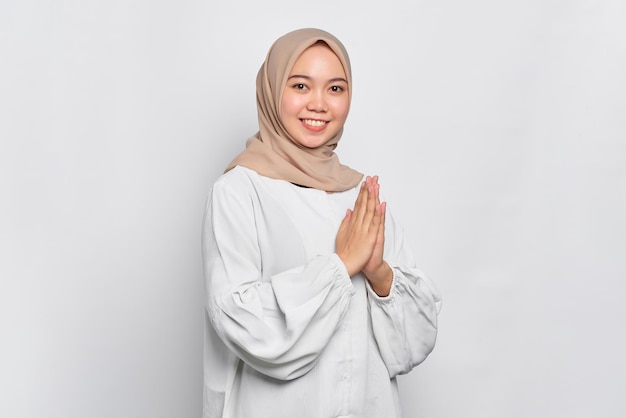 Sorridente giovane donna musulmana asiatica gesticolando Eid Mubarak saluto isolato su sfondo bianco