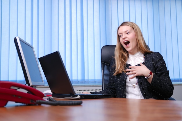 Sorridente giovane imprenditrice che lavora su un computer portatile in ufficio.