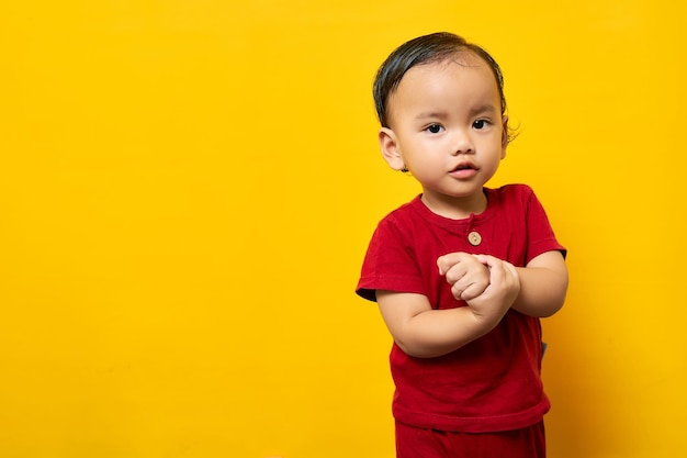 Sorridente giovane ragazzo asiatico 2 anni bambino ragazzo in maglietta rossa isolato su sfondo giallo Festa della mamma amore concetto di stile di vita familiare