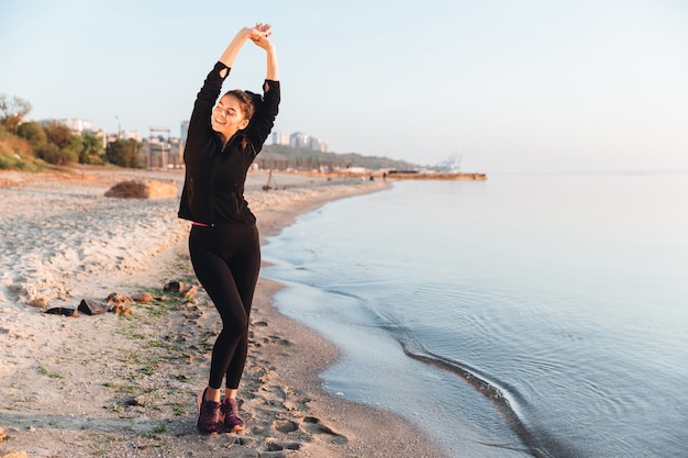 Sorridente giovane sportiva facendo esercizi di stretching