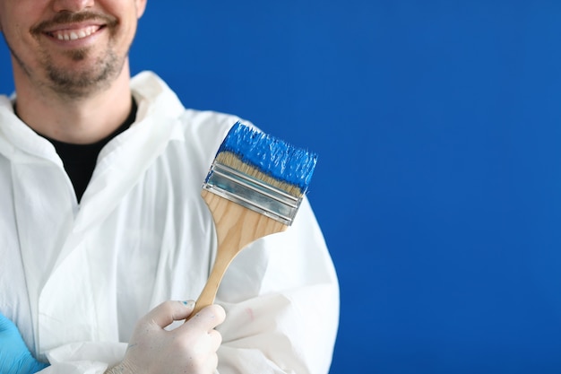 Sorridente imbianchino maestro tiene il pennello con vernice blu