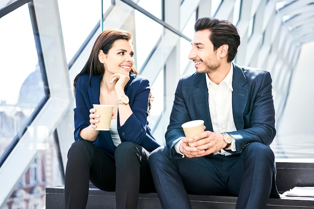 Sorridente imprenditrice e uomo d'affari con una pausa caffè in un ufficio moderno