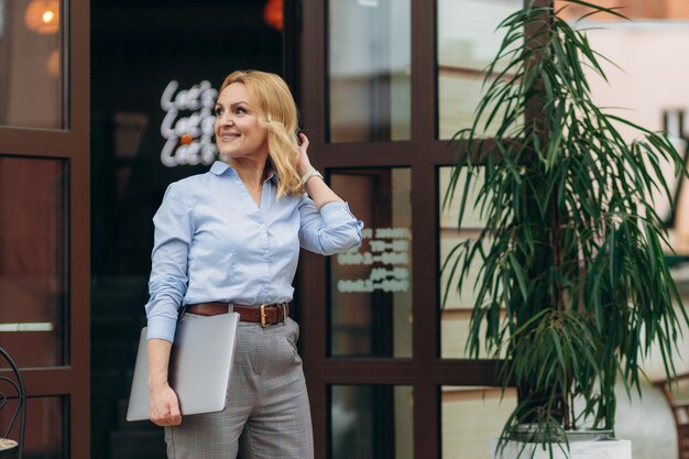 Sorridente imprenditrice matura azienda laptop contro caffe Donna di successo Concetto di lavoratore d'ufficio