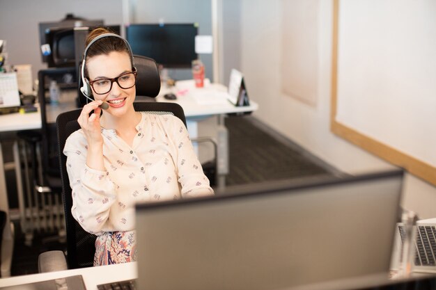 Sorridente imprenditrice utilizzando l'auricolare in ufficio