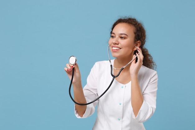 Sorridente medico afroamericano donna isolata su sfondo blu ritratto in studio. Medico femminile in abito medico con stetoscopio. Concetto di salute della medicina del personale sanitario. Simula lo spazio della copia.