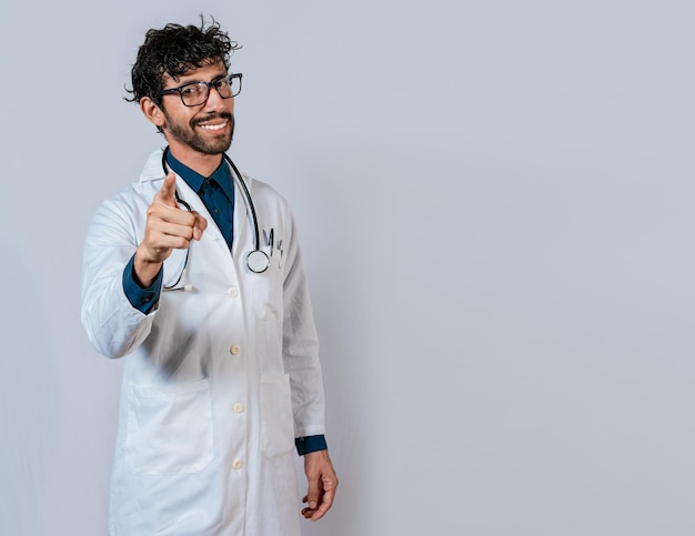 Sorridente medico che punta a te isolato Giovane medico che punta a te Amichevole medico che punta verso la telecamera