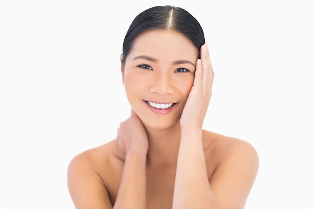 Sorridente modello dai capelli neri naturale che tocca il suo viso