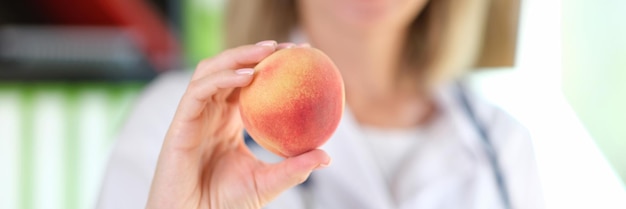 Sorridente nutrizionista femminile consiglia di mangiare frutta e cibo vegetariano per prevenire le malattie felici