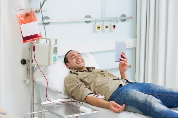 Sorridente paziente trasfuso guardando un tablet PC