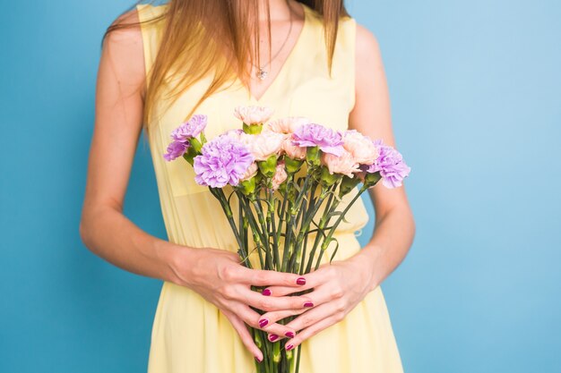 Sorridente piuttosto giovane donna con bouquet di fiori su sfondo blu.