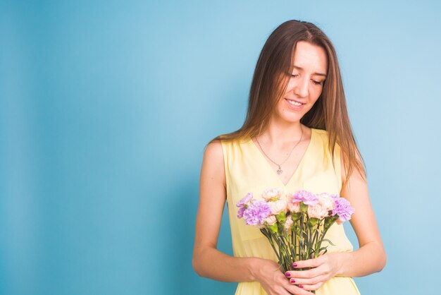 Sorridente piuttosto giovane donna con bouquet di fiori su sfondo blu.