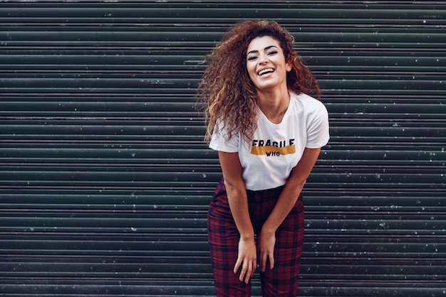Sorridente ragazza araba in abiti casual in strada.