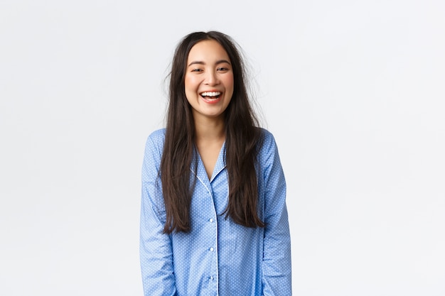 Sorridente ragazza asiatica felice ed eccitata con i capelli sudici indossando pigiami