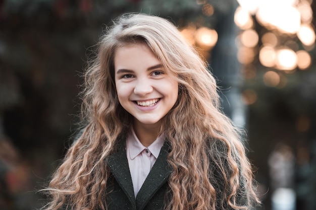 Sorridente ragazza bionda con i capelli ricci che indossa una giacca invernale