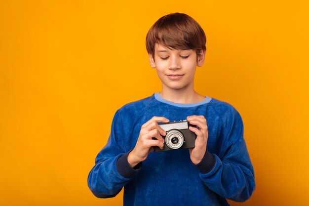 Sorridente ragazzo adolescente vuole imparare a scattare una foto con una macchina fotografica d'epoca