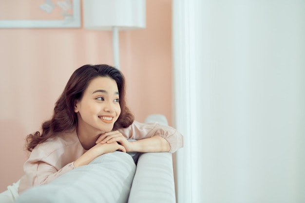 Sorridente rilassata donna attraente con gli occhiali seduto su un divano guardando indietro sopra la sua spalla