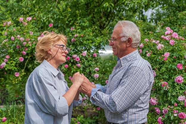 Sorridente signora senior felice e uomo che si tengono per mano. Giornata di sole primaverile o estivo.