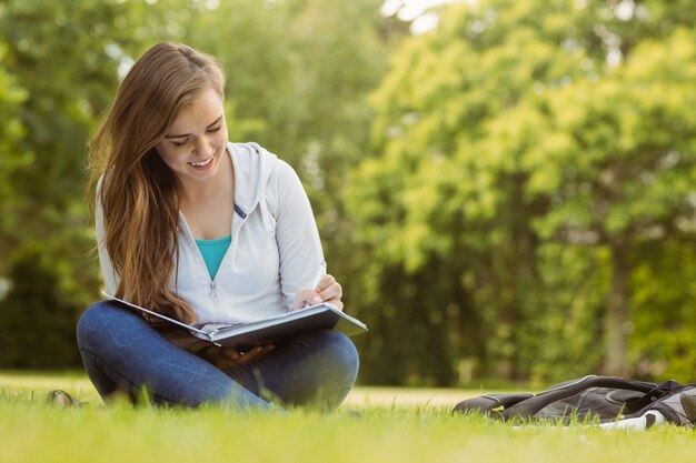 Sorridente studente seduto e leggendo il libro