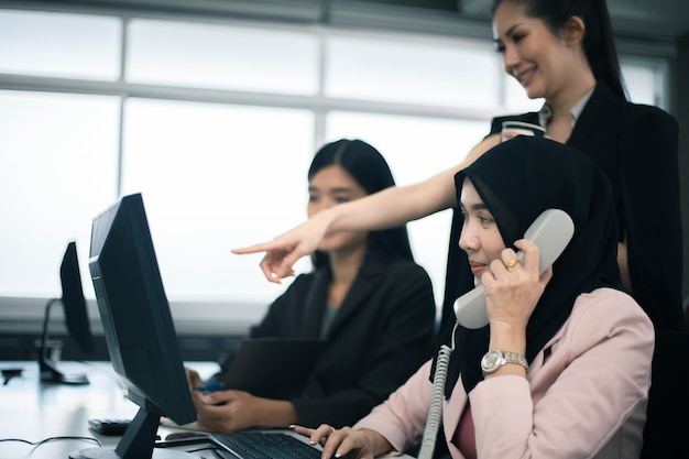 Sorridente team di donne d'affari che lavorano alla scrivania dell'ufficio e discutono di un progetto sul computer