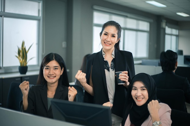 Sorridente team di donne d'affari che lavorano alla scrivania dell'ufficio e discutono di un progetto sul computer