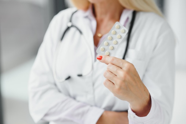 Sorridente terapista femminile di mezza età in uniforme bianca tiene le pillole