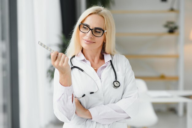 Sorridente terapista femminile di mezza età in uniforme bianca tiene le pillole