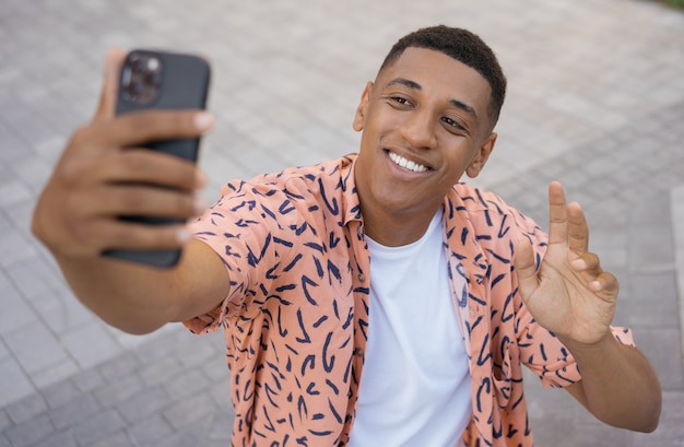 Sorridente uomo afroamericano che utilizza la comunicazione del telefono cellulare online Turista felice che prende selfie