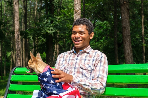 Sorridente uomo afroamericano con cane rilassato sulla panchina