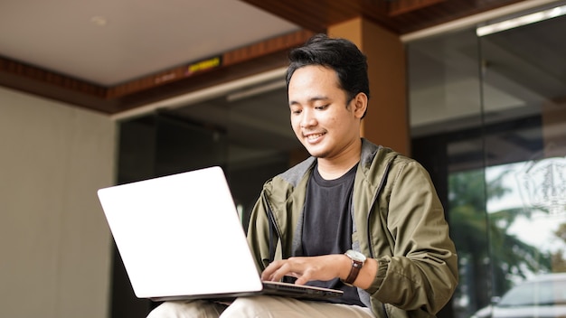 Sorridente uomo asiatico che indossa uno zaino con un computer portatile