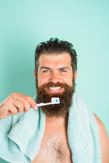 Sorridente uomo barbuto lavarsi i denti spazzolino da denti dentifricio trattamenti mattutini mattina routine salute