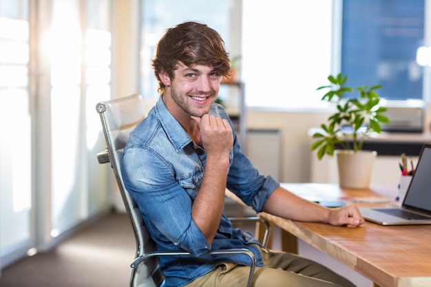 Sorridente uomo d&#39;affari casual seduto alla scrivania