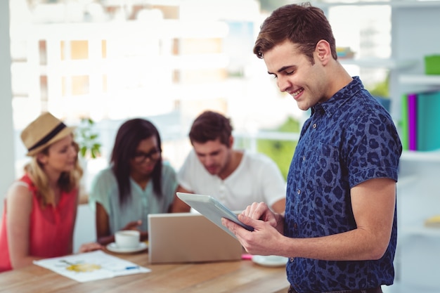 Sorridente uomo d&#39;affari creativo che lavora vicino co collaboratori