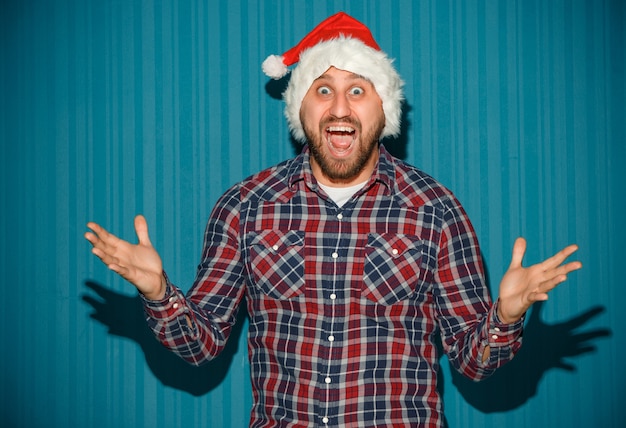 Sorridente uomo di natale che indossa un cappello da Babbo Natale sullo sfondo blu dello studio