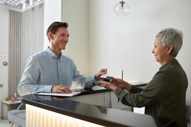 Sorridente uomo elegante che paga in clinica medica tramite tecnologia nfc