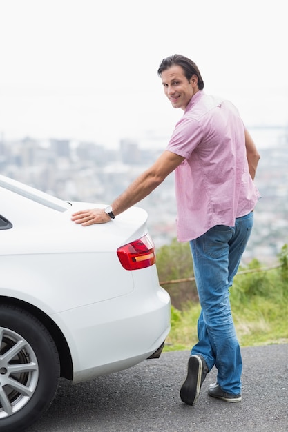 Sorridente uomo in piedi accanto alla sua auto