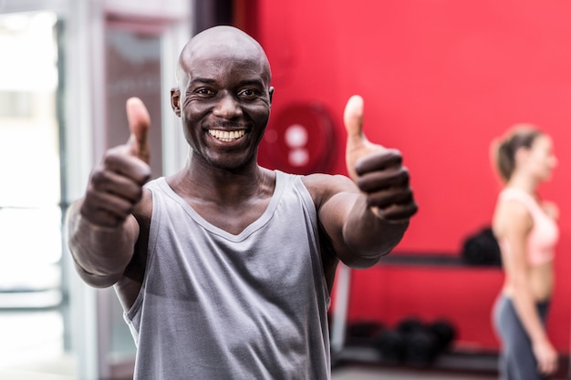 Sorridente uomo muscoloso gesticolano pollici in su