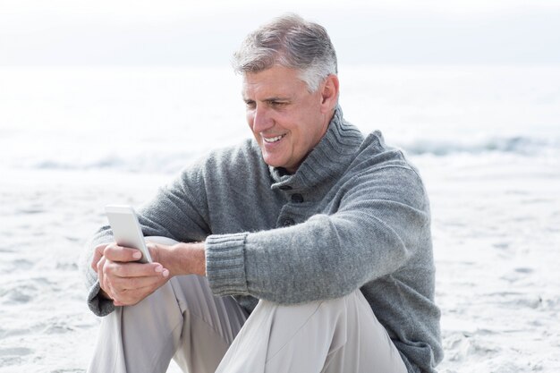 Sorridente uomo seduto e sul suo telefono