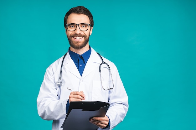 Sorridenti medico barbuto uomo ricetta di scrittura negli appunti, isolato su sfondo blu.
