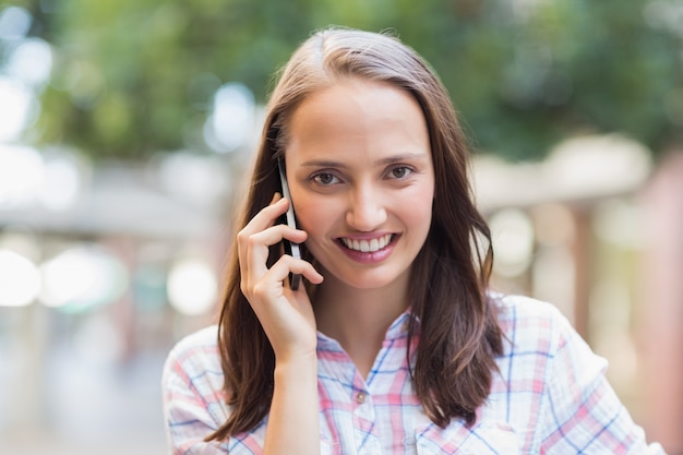 Sorridere abbastanza castana alla macchina fotografica e avere una telefonata