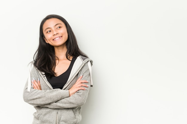 Sorridere cinese della giovane donna di forma fisica sicuro con le braccia attraversate.