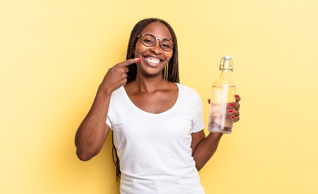 Sorridere con sicurezza che indica il proprio ampio sorriso, un atteggiamento positivo, rilassato e soddisfatto. concetto di bottiglia d'acqua