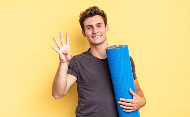 Sorridere e sembrare amichevole, mostrando il numero quattro o il quarto con la mano in avanti, conto alla rovescia. concetto di tappetino da yoga